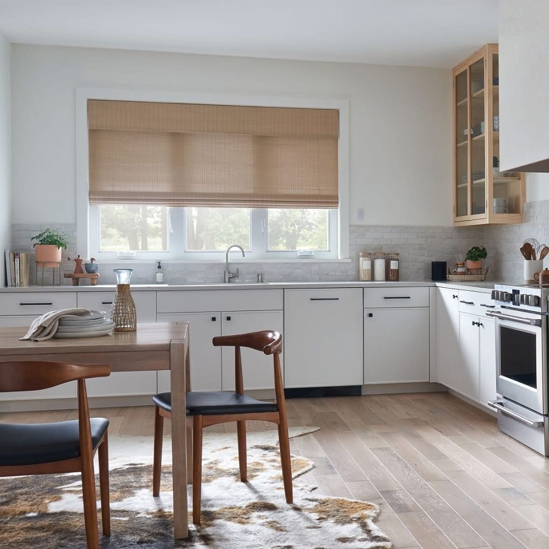 A kitchen with white cabinets and wooden floors.