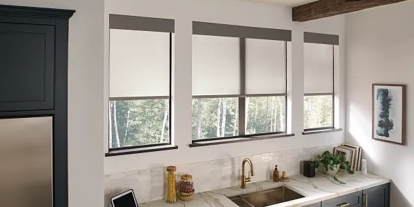 A kitchen with three windows that have blinds on them.